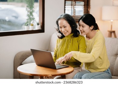 Happy adult granddaughter and senior grandmother having fun enjoying talk sit on sofa in modern living room, using a laptop, tablet bonding chatting relaxing at home  - Powered by Shutterstock