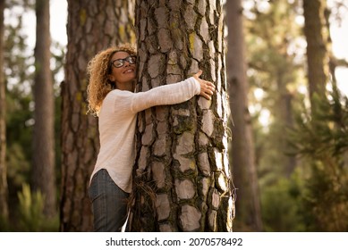 Happy adult lady hug tree trunk in outdoor leisure park activity. Concept of environment and ambient nature care. People love planet earth and stop deforestation lifestyle - Shutterstock ID 2070578492