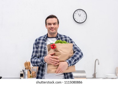 Happy Adult Man Carrying Grocery Store Bag At Kitchen And Looking At Camera