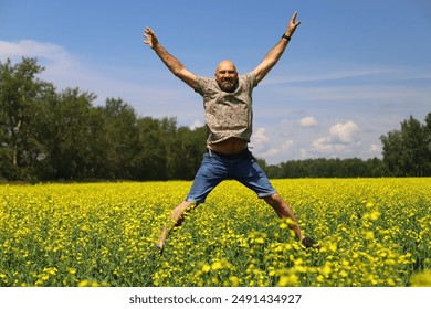 A happy adult man jumps in a yellow summer field - Powered by Shutterstock