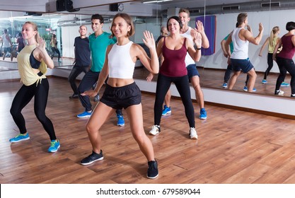 Happy adult men and ladies dancing zumba at lesson