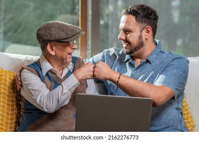Happy adult senior father with his adult son. Young man enjoys teaching his older father how to use a laptop. How to use technology.
