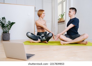 Happy Adult Siblings Doing Yoga At Home. Twisting In An Easy Pose, Looking At Each Other. Sitting On A Mat.