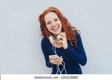 Happy Adult Woman With Red Hair And Blue Long Sleeved Shirt Laughing While Looking Straight At Camera