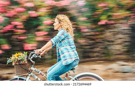 Happy Adult Woman Ride A Bike Outdoor With Flowers In Background. Environment And Green Transport With Bycicle. Cheerful Modern Female People Enjoy Active Leisure Activity Riding With A Smile