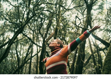 Happy adult woman smile and open arms to embrace beautiful nature forest around her. Concept of green ambient and sustainable tourism travel people. Earth's day and love for woods concept