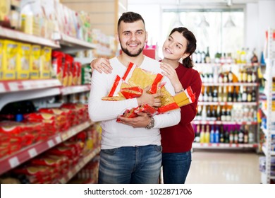 Happy Adults Reading Lable Of Pasta At Supermarket