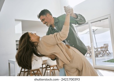 Happy affectionate loving middle aged mature couple dancing at home in kitchen. Smiling older senior man and woman in love having fun at home enjoying dance lit with sunlight. Authentic photo. - Powered by Shutterstock