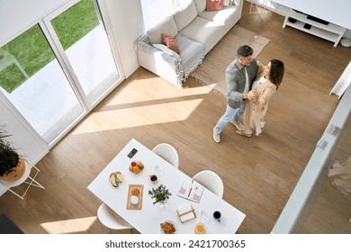 Happy affectionate romantic middle aged mature couple dancing at home. Senior older man and woman in love standing in modern house living room enjoying dance. Candid photo. Top view from above. - Powered by Shutterstock