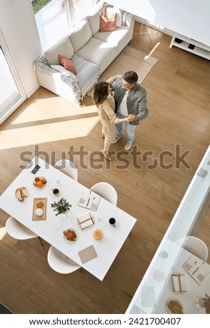 Happy affectionate romantic middle aged mature couple dancing at home. Senior older man and woman in love standing in modern house living room enjoying dance. Candid photo. Top view, vertical.