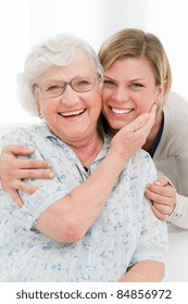 Happy affectionate senior woman embrace her granddaughter at home