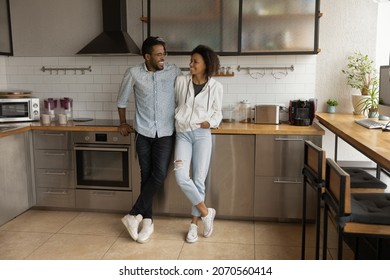 Happy affectionate young African American married family couple cuddling, enjoying communicating in modern stylish kitchen, talking speaking spending carefree weekend leisure time in own apartment. - Powered by Shutterstock