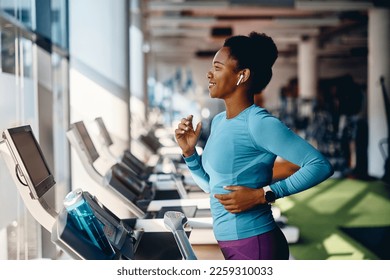 Happy African American athlete jogging on treadmill during her sports training in a gym. - Shutterstock ID 2259310033