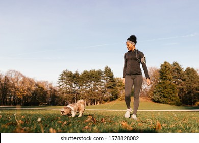 Happy African American Athletic Woman Enjoying While Walking Her Dog In Nature. 