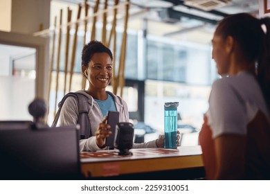 Happy African American athletic woman checking in with cell phone at reception deskin a gym. - Powered by Shutterstock