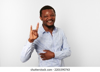 Happy African American Black Man With Sign Of Horns Gesture In Casual Bright Shirt Isolated On White Background. Smiling Adult Black Guy Portrait With Sign Of Horns, Candid Excited Male Emotion