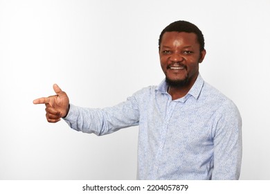 Happy African American Black Man With Pointing Finger In Casual Bright Shirt Isolated On White Background. Smiling Adult Black Guy Portrait With Pointing Finger To Left Half Size, Candid Male Emotion