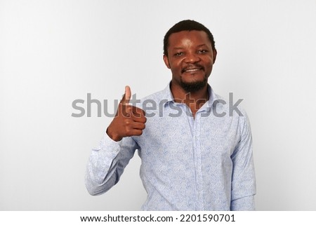Happy african american black man with thumbs up like gesture in casual bright shirt isolated on white background. Smiling adult black guy portrait with thumbs up, candid excited male emotion