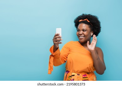 happy african american body positive woman in wireless earphones having video call on smartphone isolated on blue - Shutterstock ID 2195801373