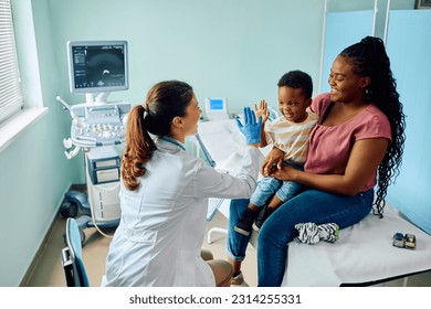 Happy African American boy giving high five to his pediatrician after medical examination at doctor's office. - Powered by Shutterstock