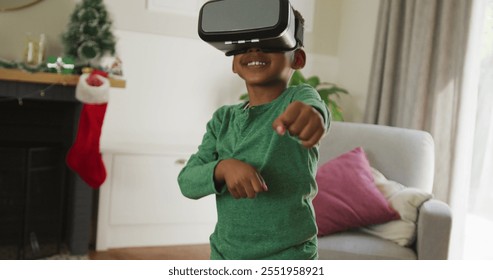 Happy african american boy wearing vr headset and having fun at christmas time. christmas, festivity and communication technology. - Powered by Shutterstock