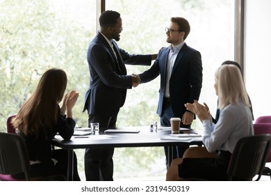 Happy African American business leader shaking hands with promoted employee. Boss hiring new team member, welcoming worker, expressing recognition for good work. Audience team clapping hands - Powered by Shutterstock