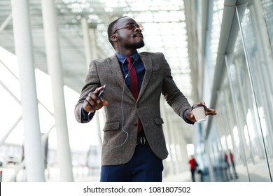Happy African American business man dances while he listens to the music in his smartphone