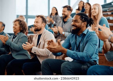 Happy African American businessman applauding after successful conference in convention center. - Powered by Shutterstock