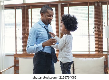 Happy African American Businessman Enjoying While Little Son Is Helping Father Tie Necktie In Living Room. African Black Family Spent Time Together In The Home.