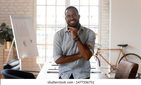 Happy African American Businessman Entrepreneur Startup Owner Stand In Modern Office Looking At Camera, Smiling Young Black Designer Creative Occupation Person Posing In Work Space, Business Portrait