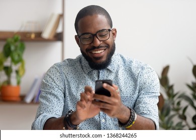 Happy african american businessman using phone mobile corporate apps at workplace texting sms, smiling black man looking at smartphone browsing internet, office technology and digital communication - Shutterstock ID 1368244265