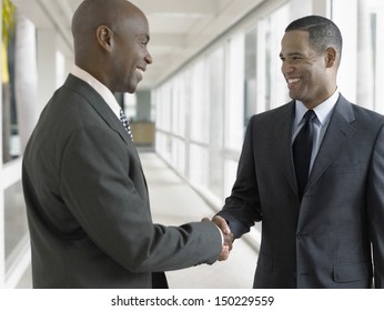 Happy African American Businessmen Shaking Hands While Standing In Office Corridor