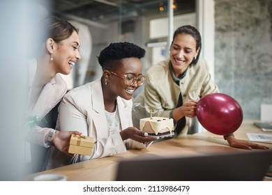 Happy African American businesswoman blowing out a candle on cake while celebrating Birthday with female coworkers in the office.  - Powered by Shutterstock