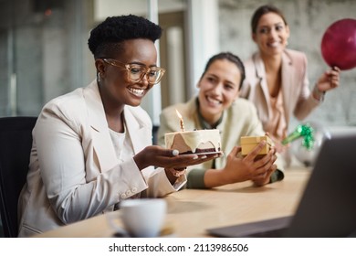 Happy African American businesswoman blowing candle on a cake while having office party with female colleagues. - Powered by Shutterstock