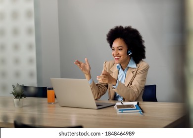 Happy African American businesswoman using computer and taking while having video conference in the office. Copy space. 
