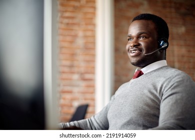 Happy African American Call Center Agent Wearing Headset While Working On A Computer In The Office.