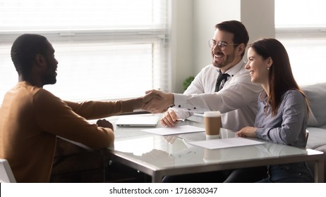 Happy african american candidate shaking hands with businessman at job interview in office. Businessman and businesswoman managers greeting client, good business partners negotiation.