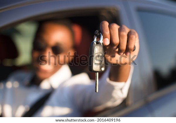happy African American in a car with a key, in\
the summer.