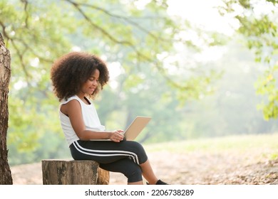 Happy African American Child Girl Using Laptop Computer Outdoors In The Park. Kid Girl Learning Outside At The School