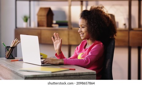 Happy African American Child Waving Hand While Having Video Chat On Laptop