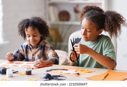 Happy African American Children Girl And Boy Making Halloween Home Decorations Together, Kids Painting Pumpkins And Making Paper Cuttings