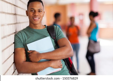 happy african american college student leaning against campus wall