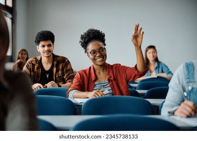 Happy African American college student raising her arm to answer the question during a lecture in the classroom.  - Powered by Shutterstock