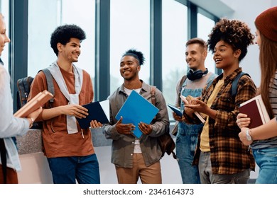 Happy African American college student talking to her classmates in a hallway. - Powered by Shutterstock