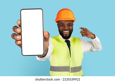 Happy African American Construction Worker Pointing At Blank Smartphone In Hand, Handsome Smiling Black Man Wearing Hard Hat And Safety Vest Demonstrating Copy Space For Mockup, Creative Collage