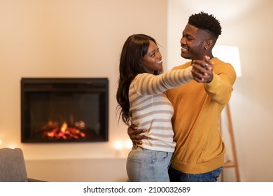 Happy African American Couple Dancing Near Fireplace Having Fun Celebrating Valentine Day Or Family Holiday Having Date At Home. New Year And Christmas Celebration Concept - Powered by Shutterstock