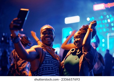 Happy African American couple dancing and taking selfie with cell phone during summer music festival.  - Shutterstock ID 2336657693