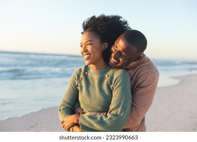 Happy african american couple embracing and smiling on sunny beach. Summer, togetherness, romance and vacation, unaltered. - Powered by Shutterstock