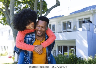 Happy african american couple riding piggyback in sunny garden, copy space. Outdoors, expression, love, togetherness and nature, unaltered. - Powered by Shutterstock