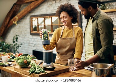 Happy African American couple using blender while preparing healthy smoothie in the kitchen.  - Powered by Shutterstock